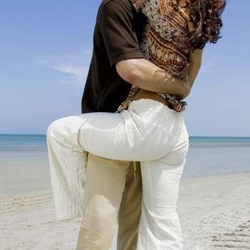 Mid section view of a man and a woman embracing each other on the beach