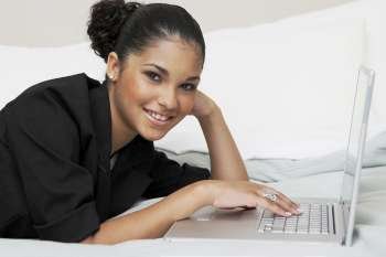 Portrait of a young woman using a laptop on the bed