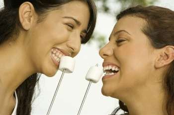 Close-up of two teenage girls eating marshmallows