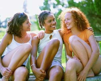 Close-up of three young women sitting on a bench and smiling, Bermuda