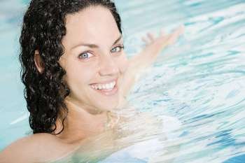 Portrait of a young woman smiling with her arms outstretched in a swimming pool