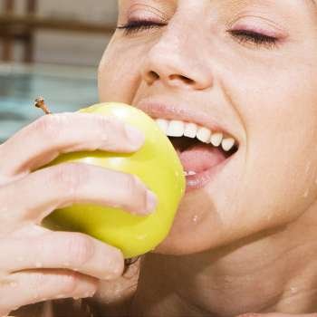 Close-up of a young woman eating a green apple in a swimming pool