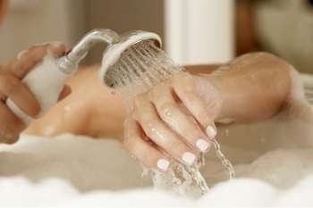 Close-up of a young woman´s hands holding a shower head