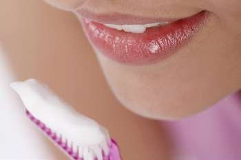 Close-up of a young woman with a toothbrush in front of her mouth