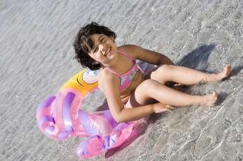 Girl sitting on an inflatable ring on the beach