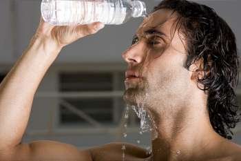 Close-up of a mid adult man pouring water on his face