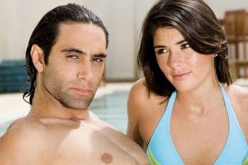 Close-up of a mid adult man and a young woman at the poolside