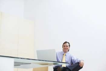 Portrait of a businessman sitting in an office with a laptop in front of him