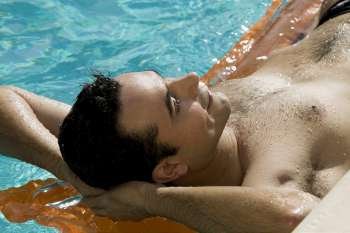 Close-up of a young man lying on a raft in a swimming pool