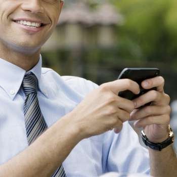 Close-up of a businessman using a personal data assistant and smiling