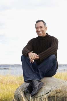 Portrait of a mature man sitting on a rock and smiling