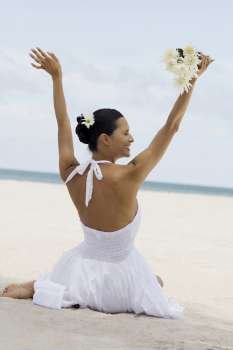 Rear view of a young woman holding flowers on the beach
