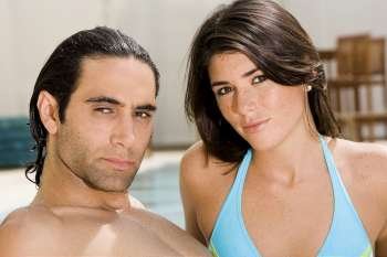 Portrait of a mid adult man and a young woman at the poolside