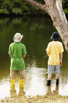 Rear view of two teenage boys fishing in a lake