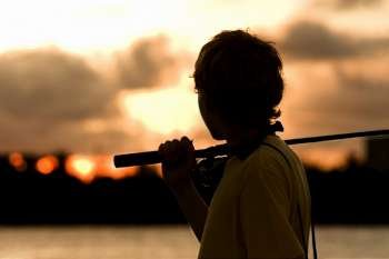 Side profile of a boy carrying a fishing rod