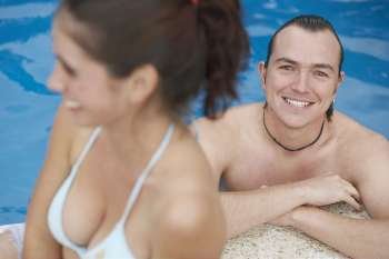 Mid adult man and a young woman smiling in a swimming pool