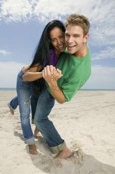Portrait of a young couple smiling and standing on the beach