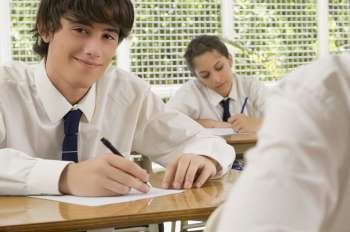 Portrait of a young man writing on paper sheet and smiling with a teenage girl behind him