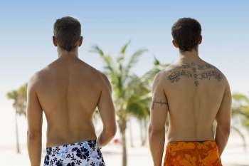 Rear view of two men standing on the beach