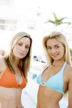 Portrait of two young women standing at the poolside