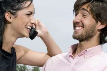 Young woman talking on a mobile phone with a young man smiling