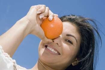 Portrait of a mid adult woman holding an orange and smiling