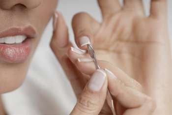 Close-up of a young woman cleaning her fingernails