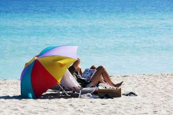 Two people under a beach umbrella, Miami, Florida, USA