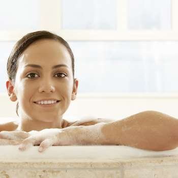 Portrait of a young woman leaning at the edge of a bathtub