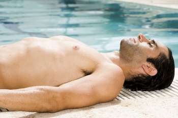 Side profile of a mid adult man sunbathing at the poolside