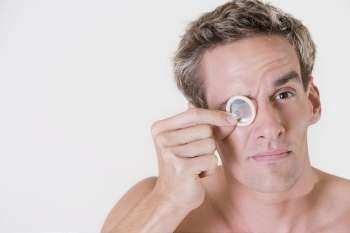 Close-up of a young man looking through a condom