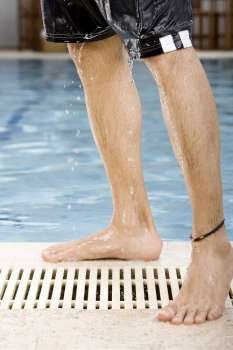 Low section view of a mid adult man standing at the poolside