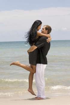 Side profile of a young couple embracing each other on the beach