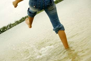 Low section view of a woman kicking water on the beach