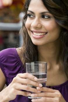 Close-up of a young woman holding a glass of water and smiling
