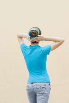 Rear view of a teenage girl standing with her hands behind her head