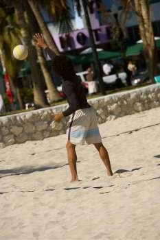 Rear view of a man playing volleyball on the beach, Miami Beach, Florida, USA