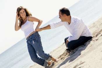 Portrait of a young woman and a mid adult man romancing on the beach