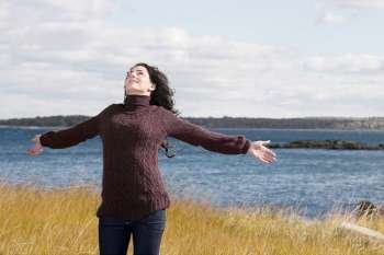 Mature woman standing on the beach with her arms outstretched