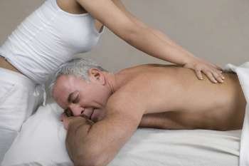 Side profile of a senior man receiving a back massage from a massage therapist
