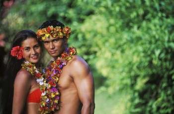 Portrait of a young couple standing together wearing garlands, Hawaii, USA