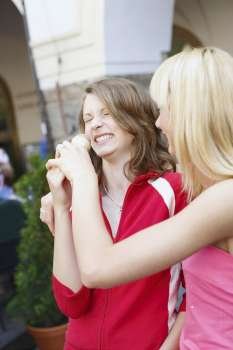 Close-up of a teenage girl holding an ice-cream in front of another woman