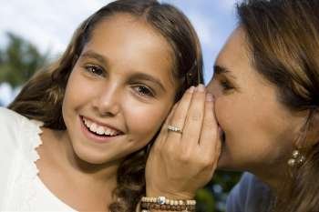 Close-up of a mid adult woman whispering into her daughter´s ear