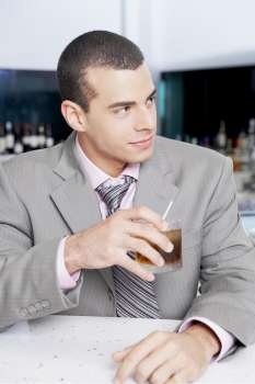 Close-up of a businessman holding a glass of cocktail in a bar