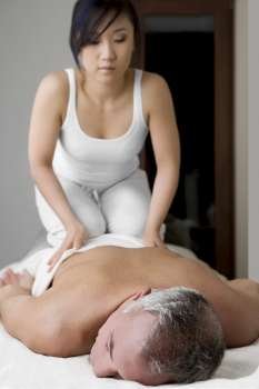 Rear view of a senior man getting a back massage from a massage therapist