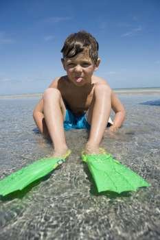 Portrait of a boy wearing flippers and sticking his tongue out