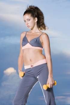 Portrait of a young woman holding dumbbells