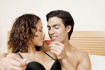 Close-up of a young man feeding a strawberry to a teenage girl