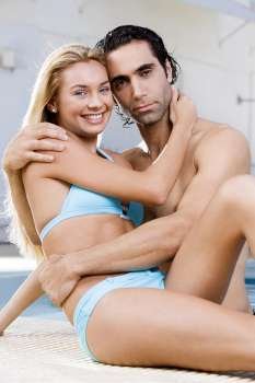 Portrait of a young woman and a mid adult man embracing at the poolside