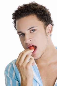 Portrait of a young man eating a strawberry